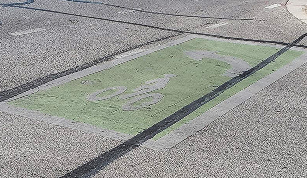Green pavement with outline of a bicycle to indicate a bicycle lane.
