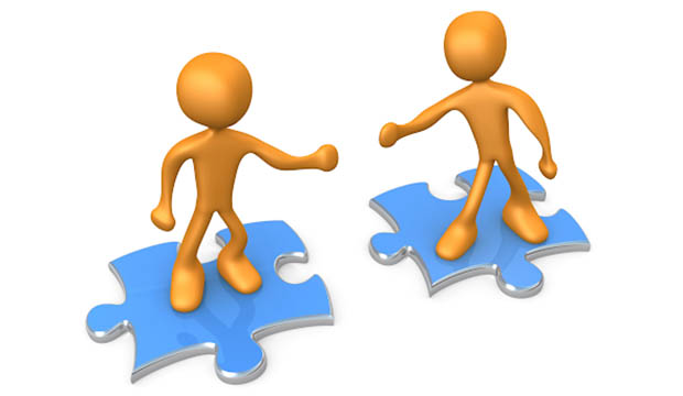 Two minions standing on jigsaw puzzles, reaching out to each other