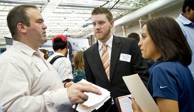 Three young adults talking to each other at a career fair.