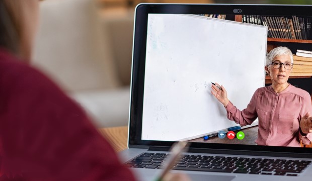 A computer screen shows a teacher writing on a whiteboard.