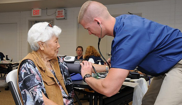 Elderly woman having her blood pressure tested by young male nurse.