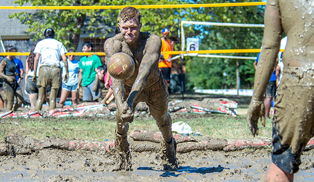 A student jumps to hit the ball in Oozeball mud volleyball tournament 2019