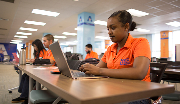 Young woman typing on laptop computer in UTA's Central Library.