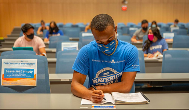 Black student wearing a face mask in a classroom with socially distanced students.