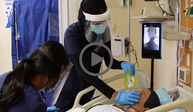 Nursing students working on a maniken with a telepresence robot beside them.