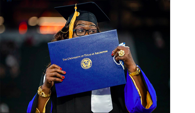 Graduate holding diploma in front of her mouth.