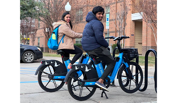 Two students on bicycles that are part of UTA's new bikeshare program.
