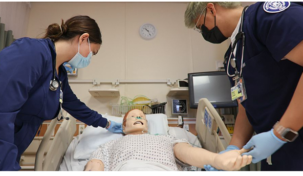 Two nursing students working on a patient maniken.
