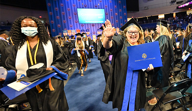 Graduates leaving commencement ceremonies with their diplomas in hand.
