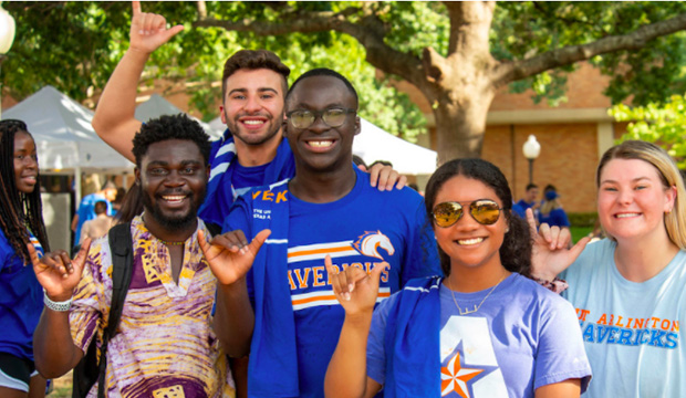 Group of diverse students giving the Maverick hand sign.