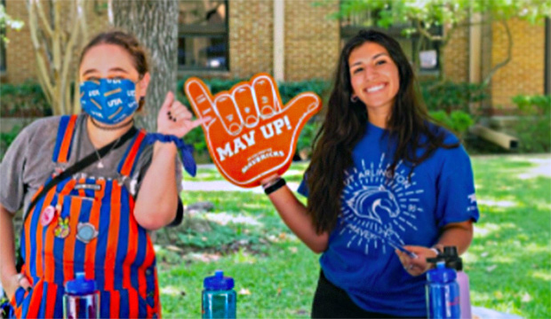 Two students giving Mav hand sign.