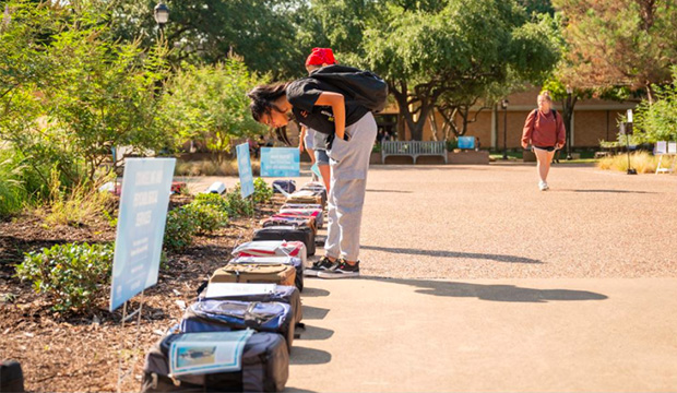 Student looking at backpacks on ground that are part of the Send Silence Packing exhibit for suicide prevention.