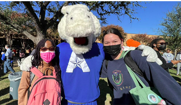 Blaze with his arms around two female students.