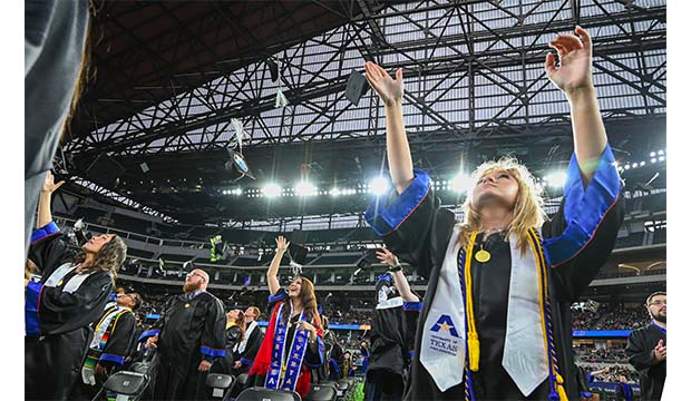 Graduates throw their mortar board into the air at Commencement ceremonies for fall 2021 at Globe Life Field.