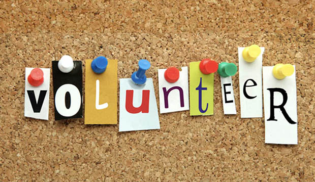 'Volunteer' spelled out with cut out letters pinned to a cork board.