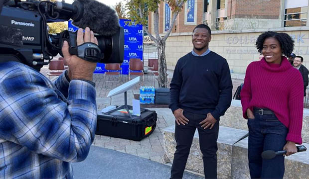 Two communication students stand in front of an NBC News cameraman.