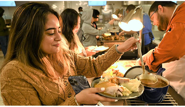 Female student pouring gravy on her Thanksgiving plate of food.