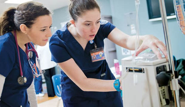 Two nursing students working on an IV machine.