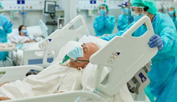 Nurse pushing a hospital bed with a man wearing an oxygen mask.