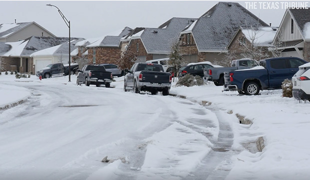Snow covering street, yards, and vehicles in residential neighborhood.