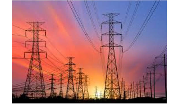 Sun setting behind rows of electricity transmission towers.