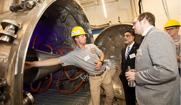 Engineer showing the inside of the hypersonic wind tunnel to UTA President Vistasp Karbhari and others.