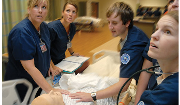 Nursing students around a manikin looking at monitors