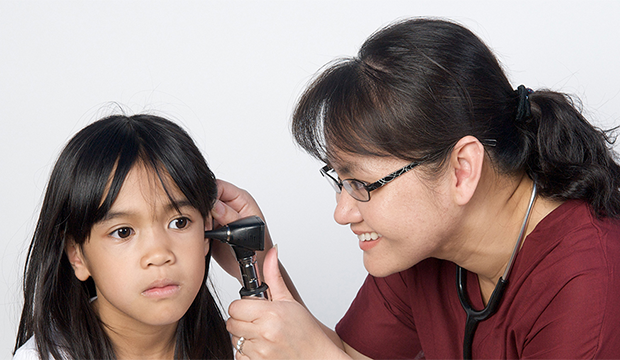 Public health nurse looking into a child's ear with scope.