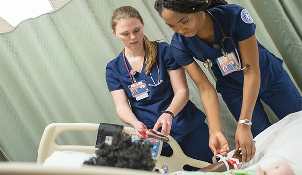 Two nursing students examining a patient maniken.