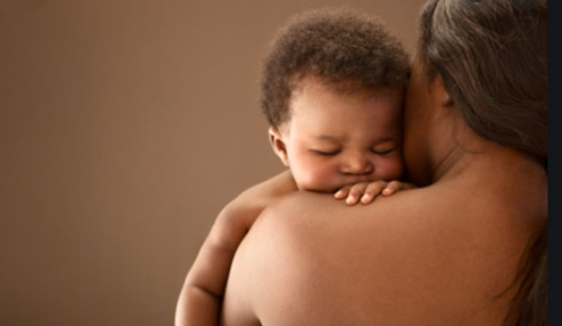 Black baby being held by its Black mother.