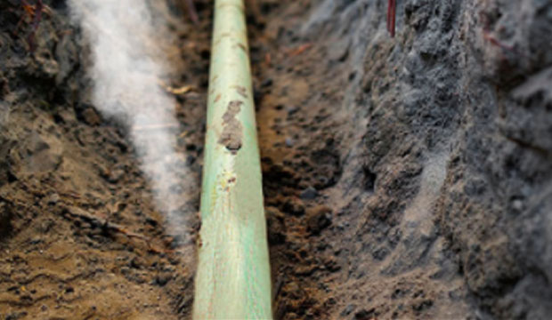A green gas pipe with a leak, showing an airy leak of natural gas.