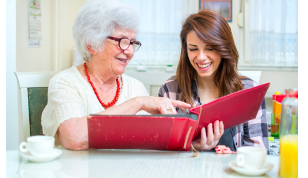 Older woman showing point to a photo album with a young woman.