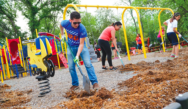 Volunteers raking mulch on playground.
