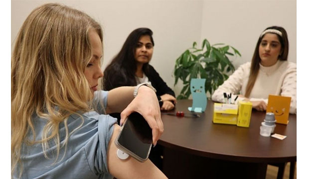 Woman taking reading from device on arm.