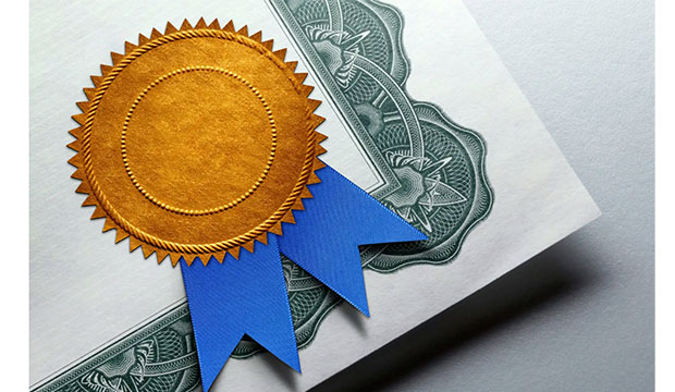 Corner of a certificate with gold emblossed star and ribbon.