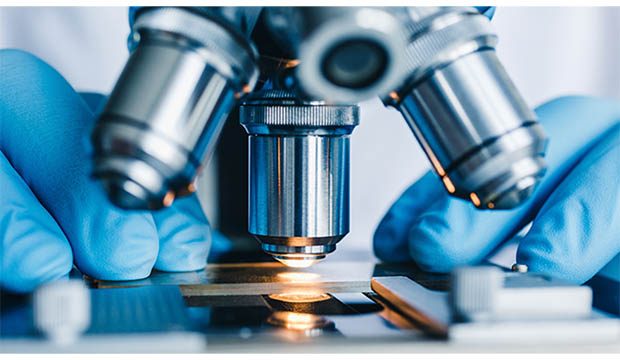 Closeup of microscope lens pointed at slide.