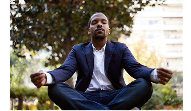 Man in suit sitting in lotus pose.