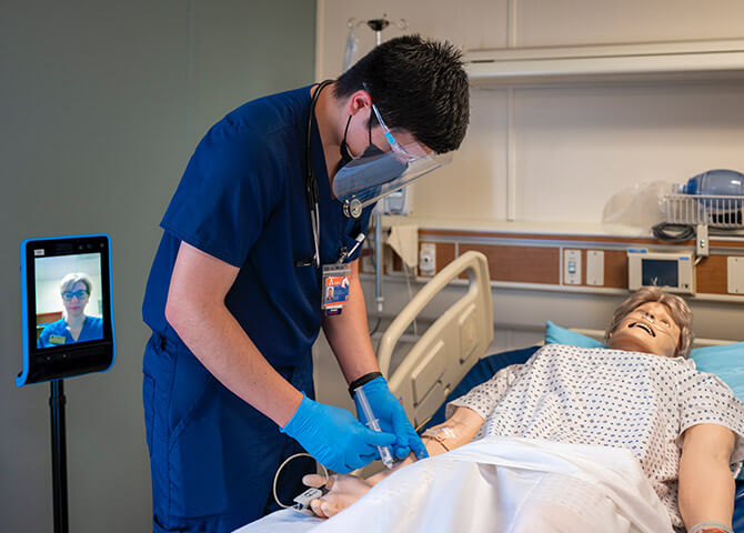 Man in doctors attire practicing on medical dummy