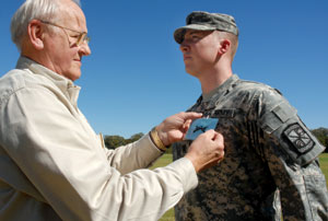 Lt. Col. Andrae presents the crossed-rifles pin to cadet Ryan Kelly
